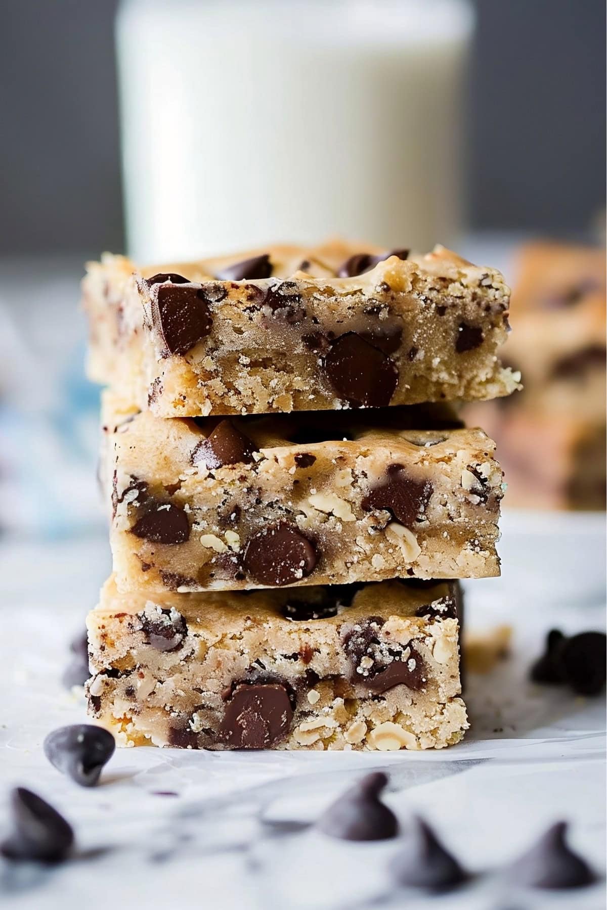 Stack of square slices of Chocolate Chip Cookie Bars on a white marble table.