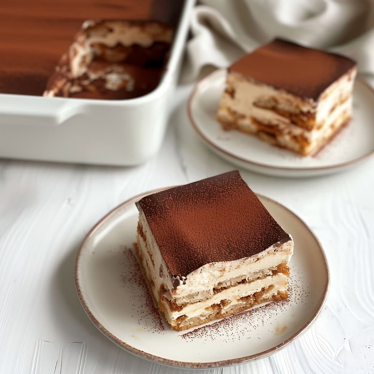 Square slice of Chocolate Tiramisu served on a white plate.