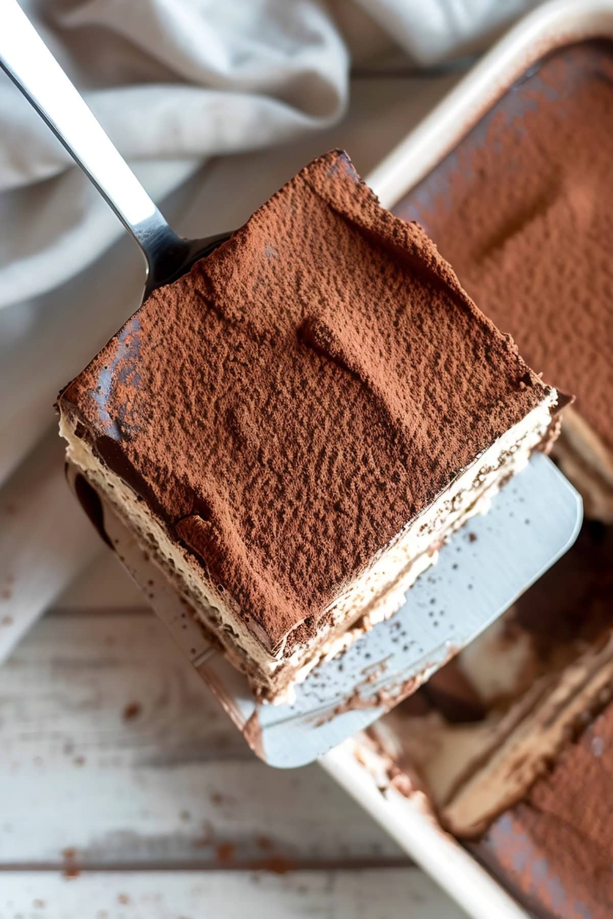 Pie ladle lifting a square slice of Chocolate Tiramisu.