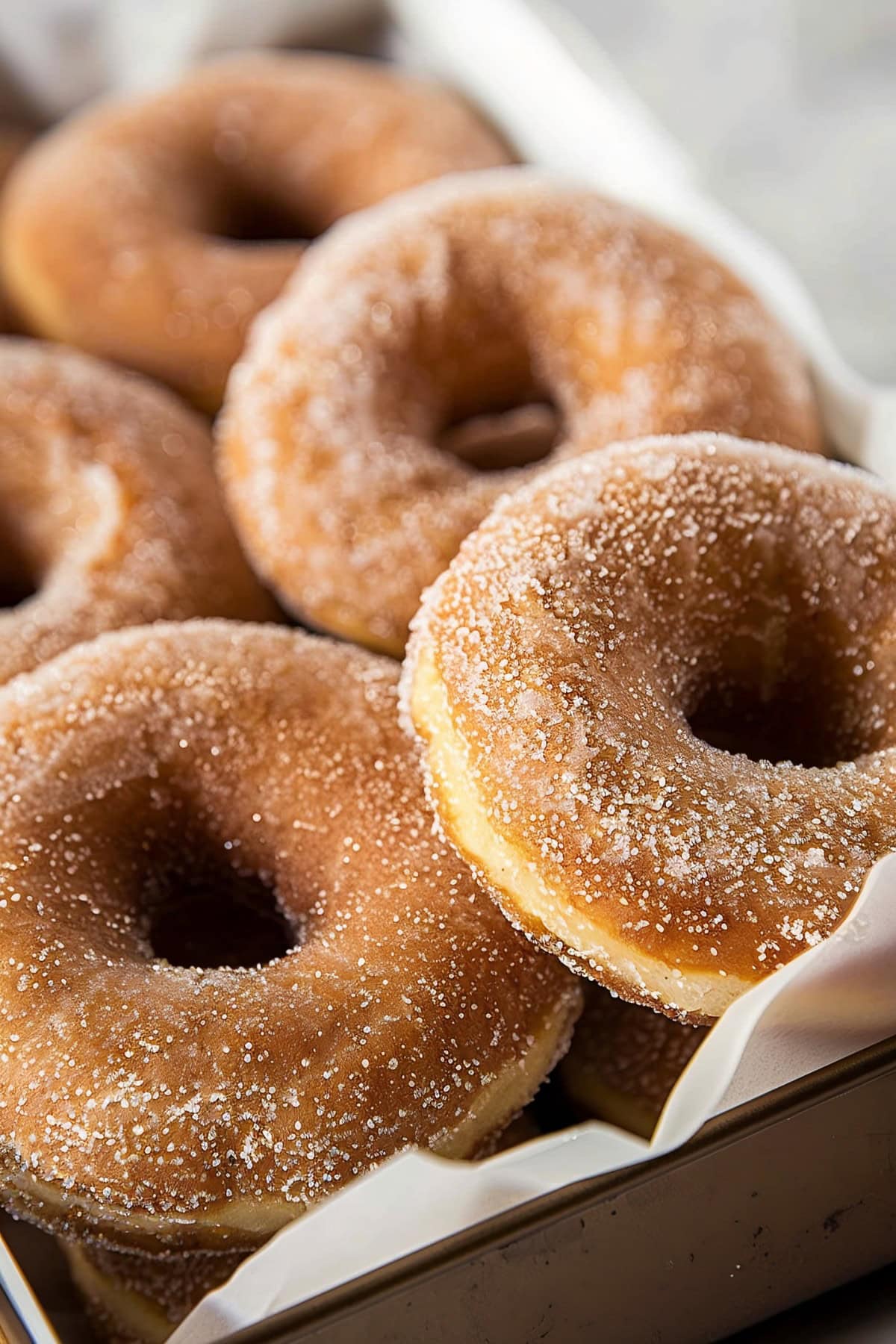 Cinnamon sugar donuts in a baking tray with parchment paper