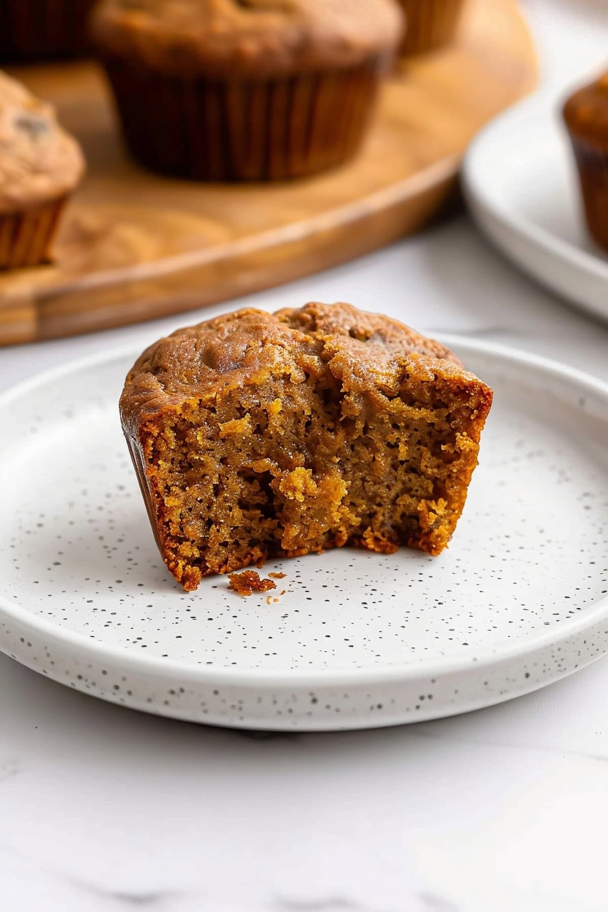 Sliced pumpkin banana muffin cut in half to show the moist sponge, on a plate