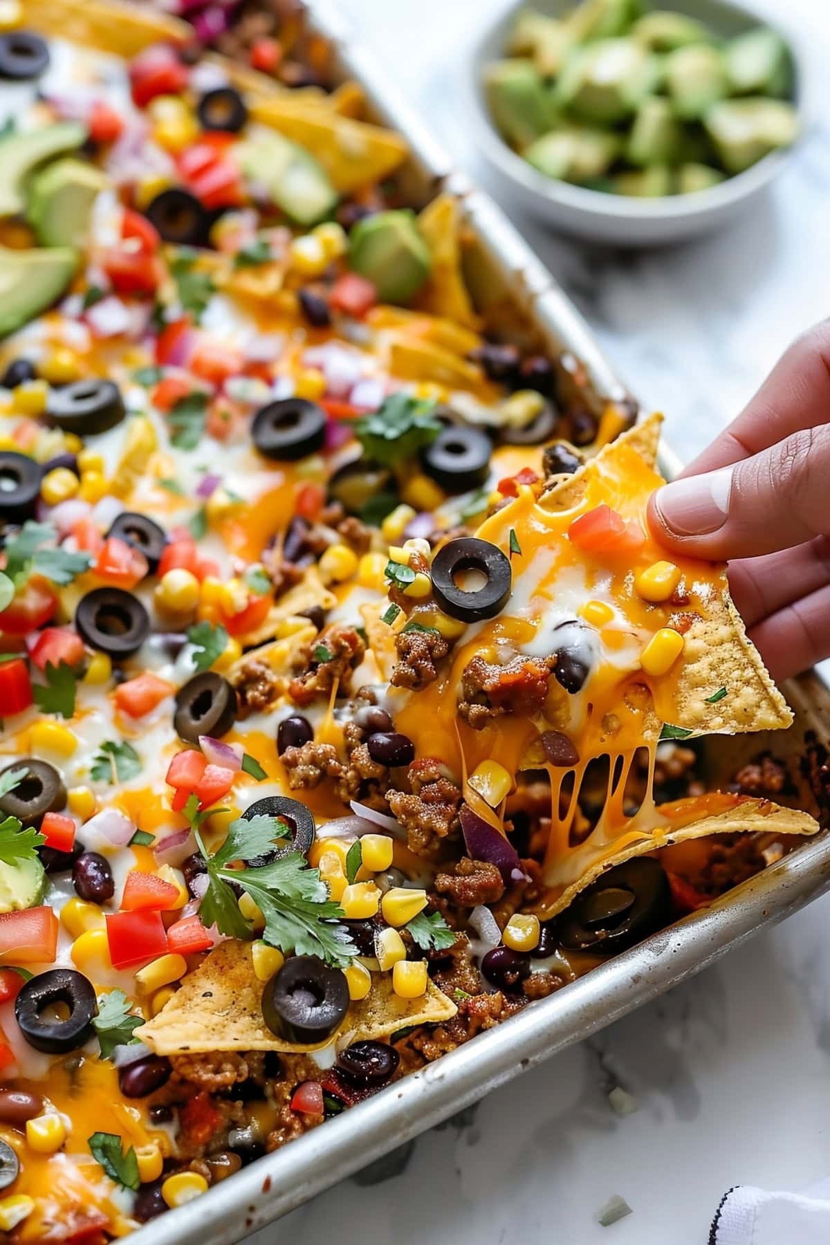 A Hand Picking Chips into a Sheet Pan Nachos.