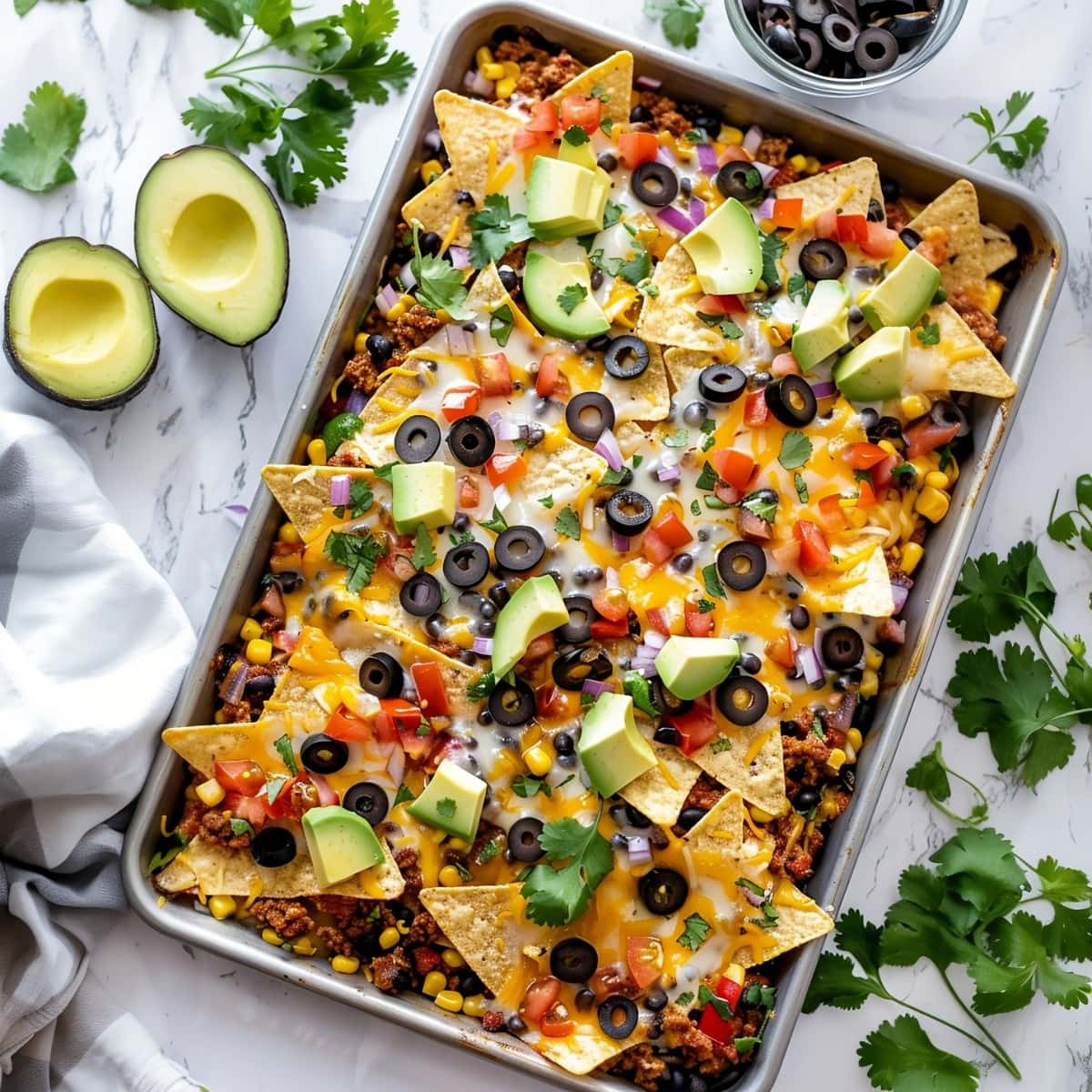 Sheet Pan Nachos with Tomatoes, Black Beans and Avocados, Garnished with Cilantro.