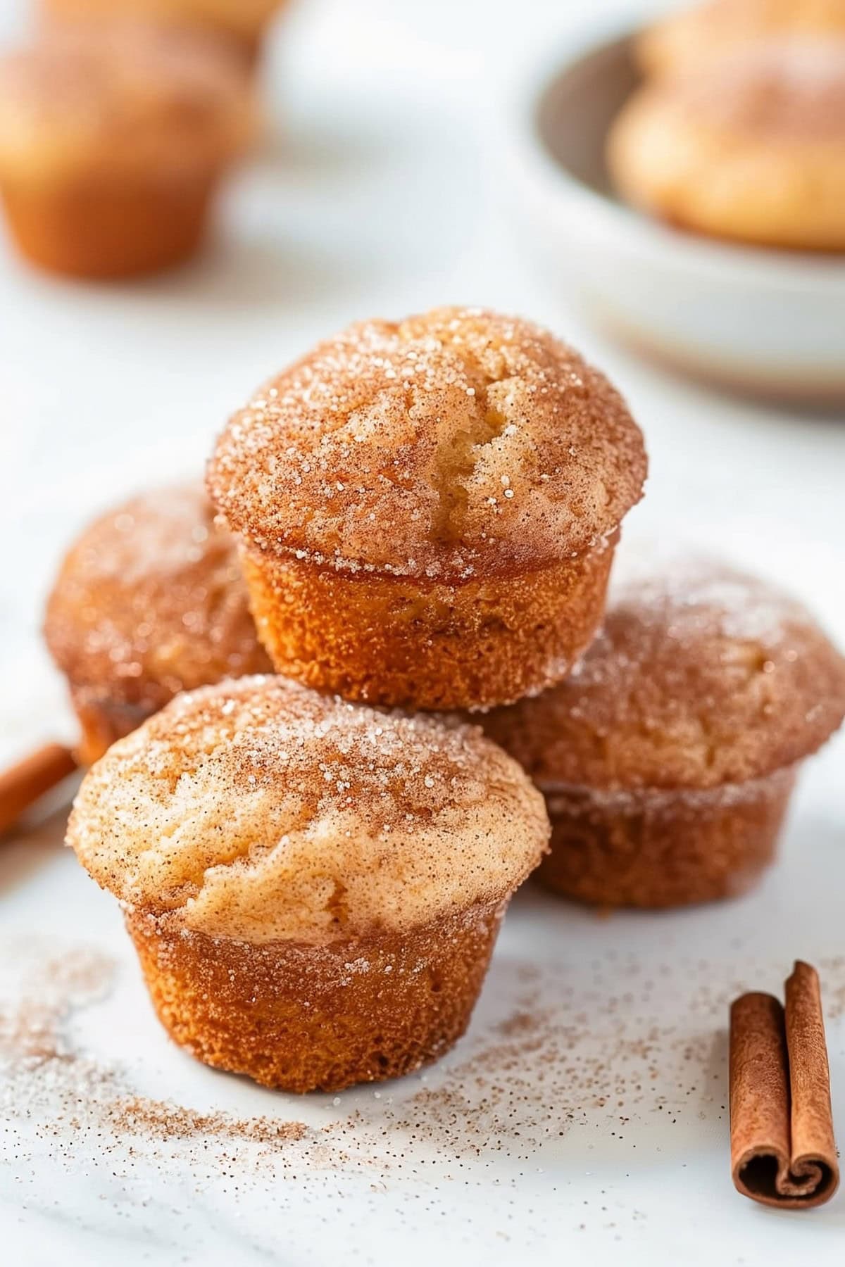 Stack of Snickerdoodle muffins sitting on a white marble table.