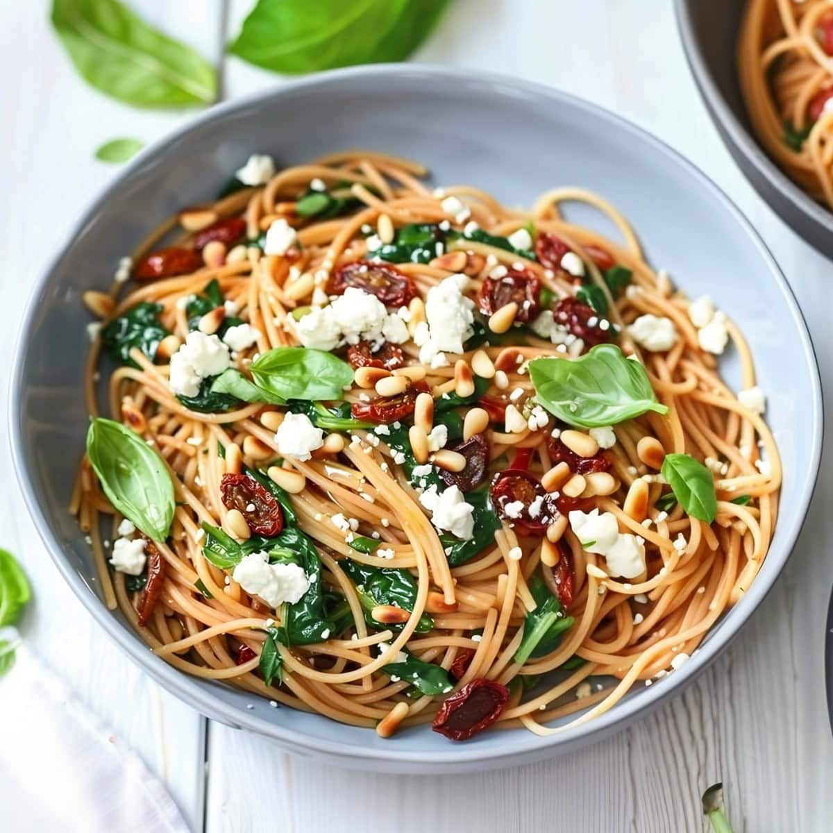 Flavorful spaghetti dish featuring sun-dried tomatoes and vibrant spinach leaves.