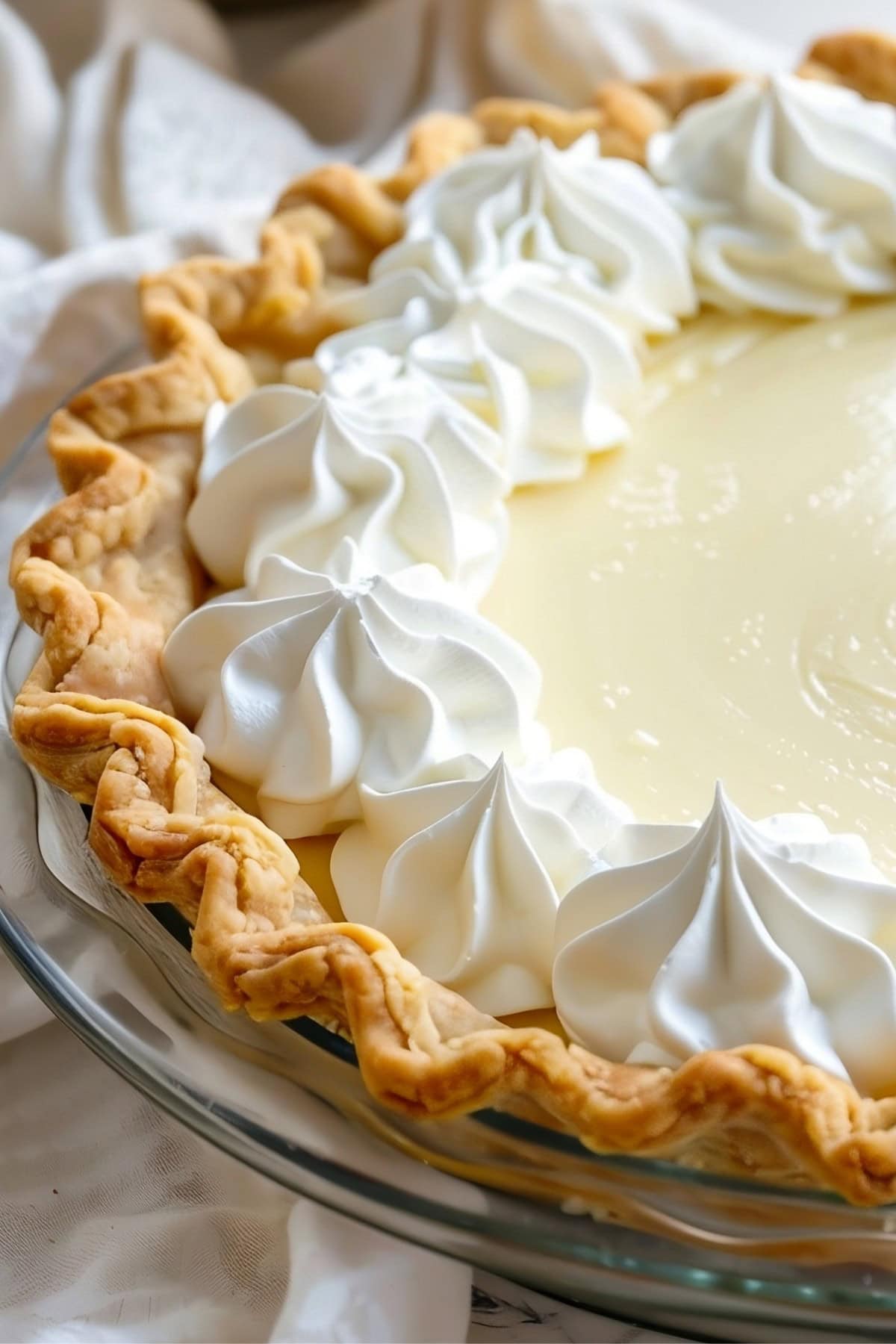 Whole vanilla cream pie in a glass pie dish.