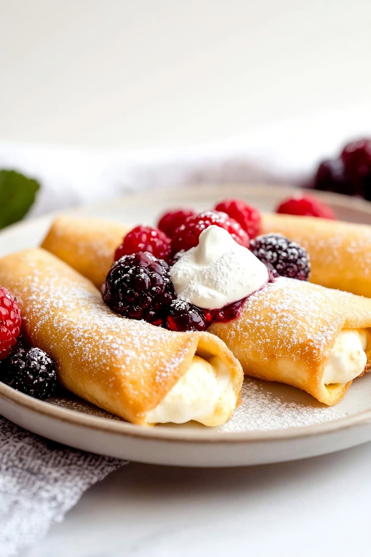 Cheese blintzes rolled up and garnished with fresh berries, sprinkled with powdered sugar.