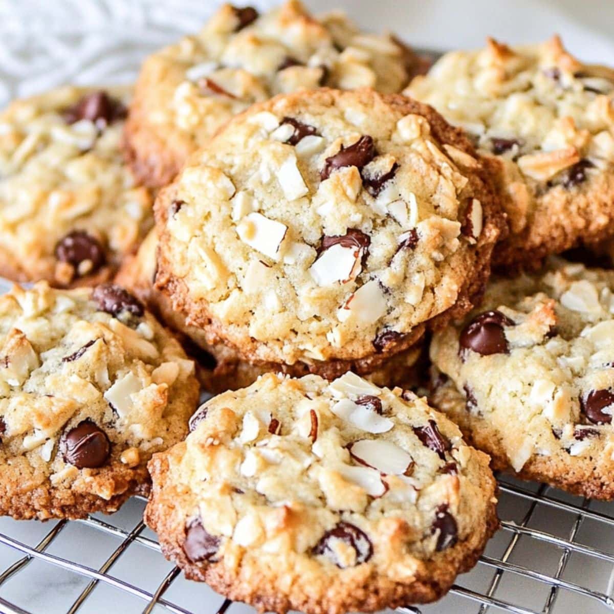 Bunch of crispy almond joy cookies with chocolate chips in a cooling rack.