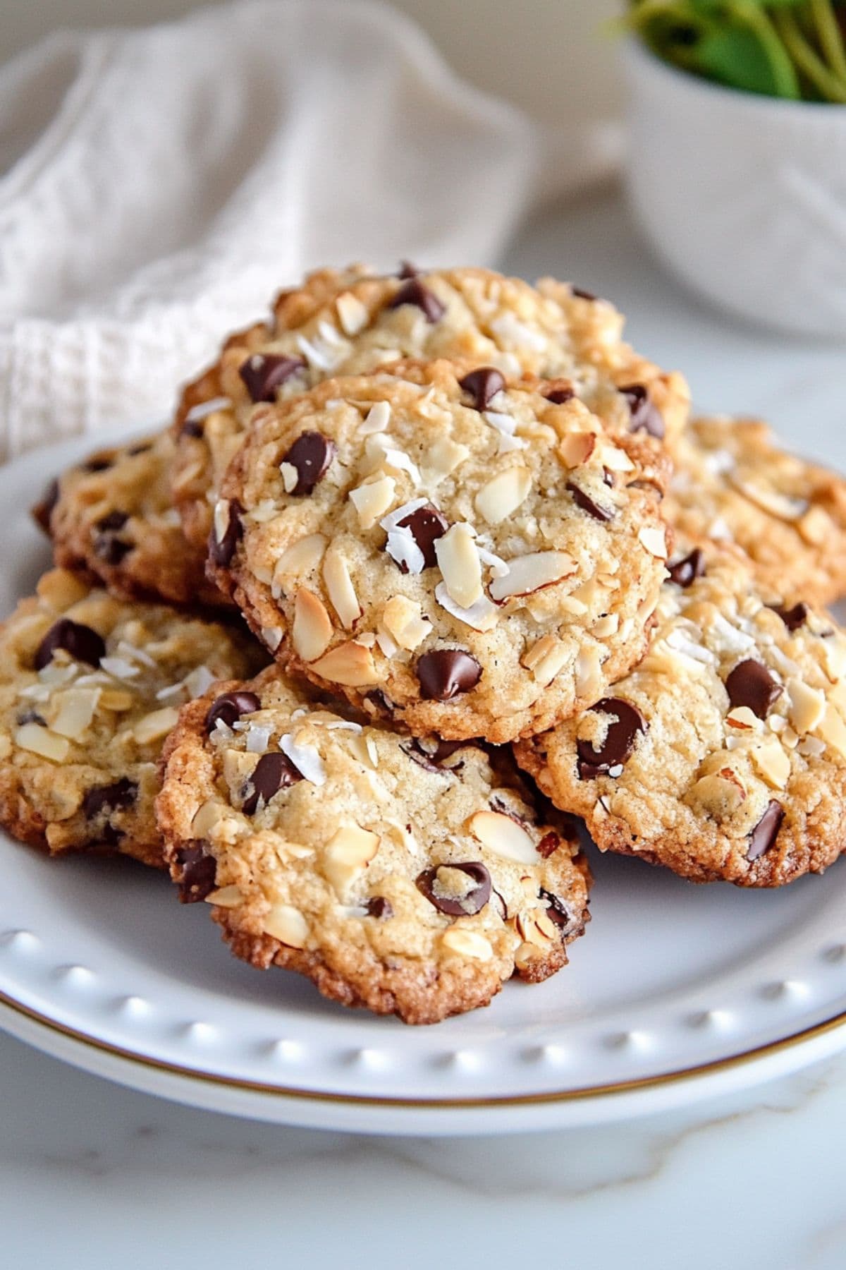 Bunch of almond joy cookies with chocolate chips, coconut flakes and chopped almonds served on a white plate.