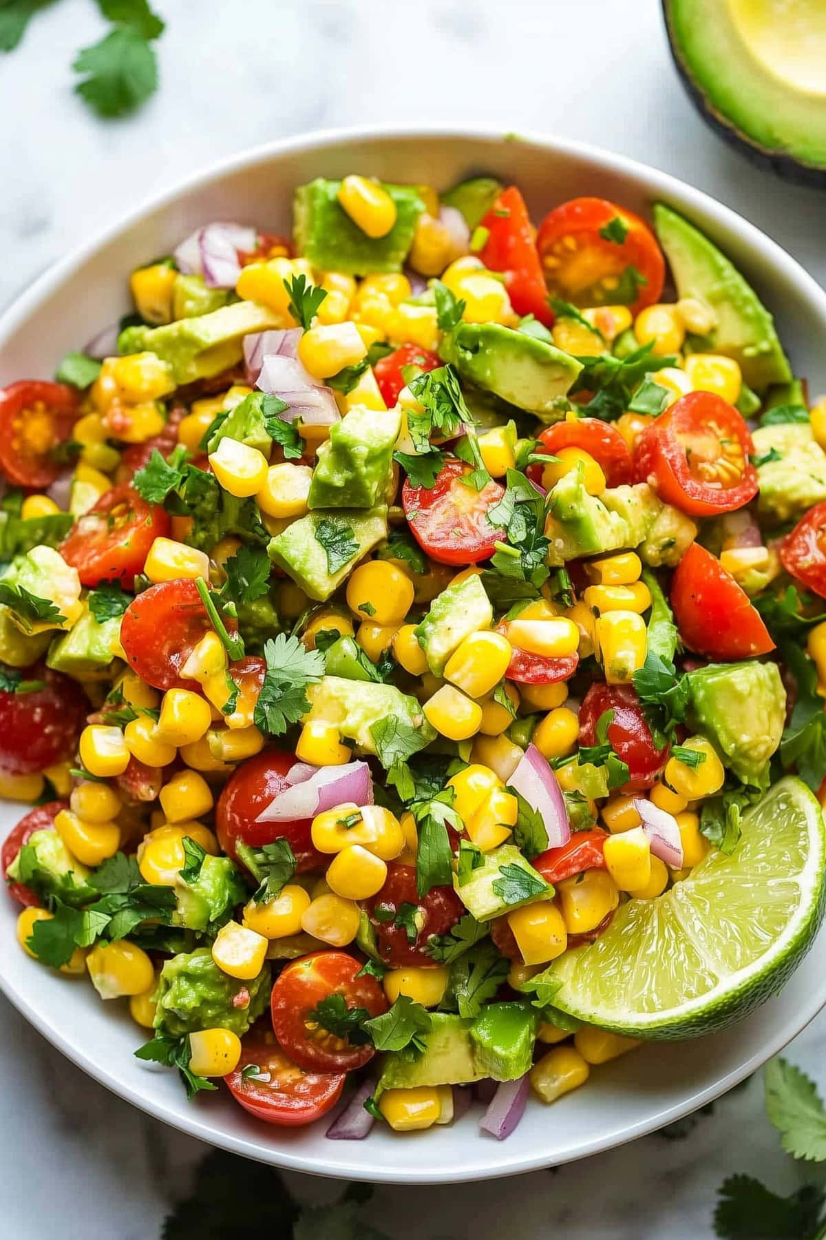 Homemade avocado corn salad with cherry tomatoes and red onions.