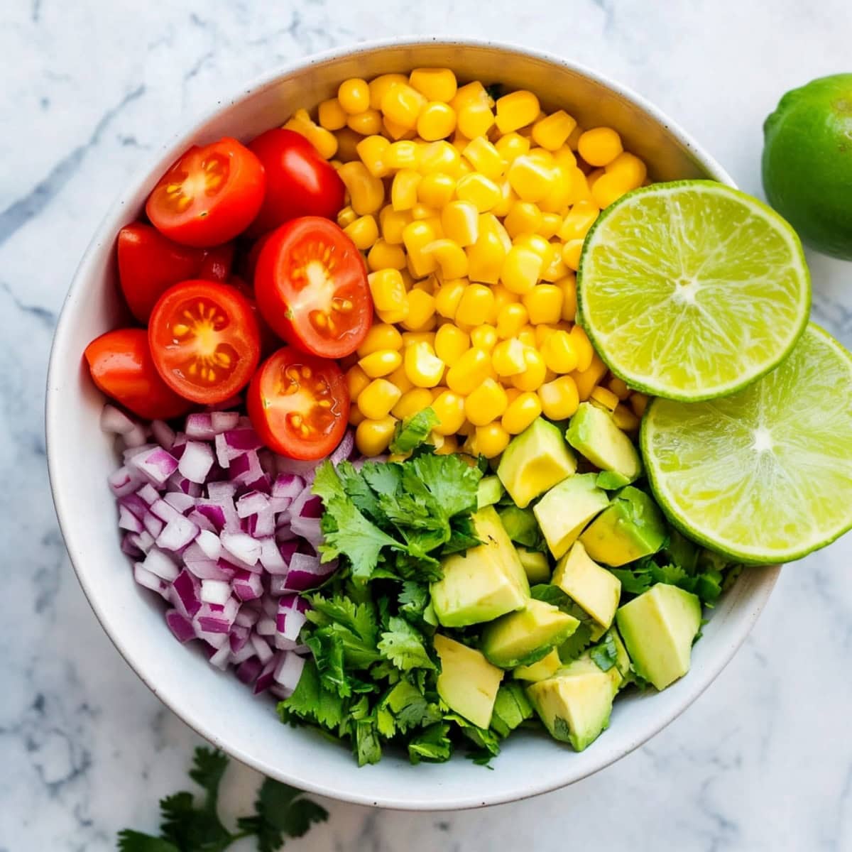 A bowl of fresh avocados, corn, tomatoes, red onions and cilantro.