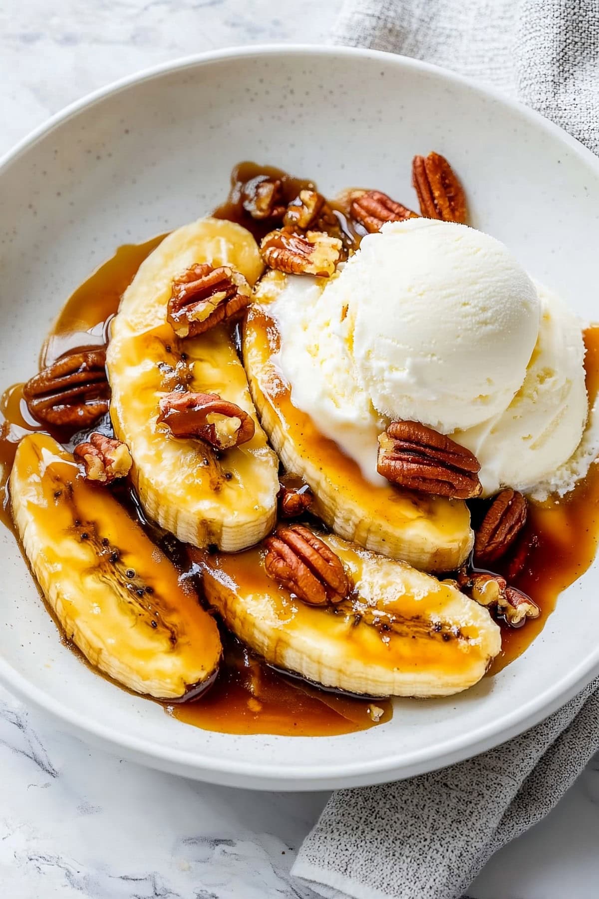 Bananas Foster with caramel served in a bowl with ice cream and pecans