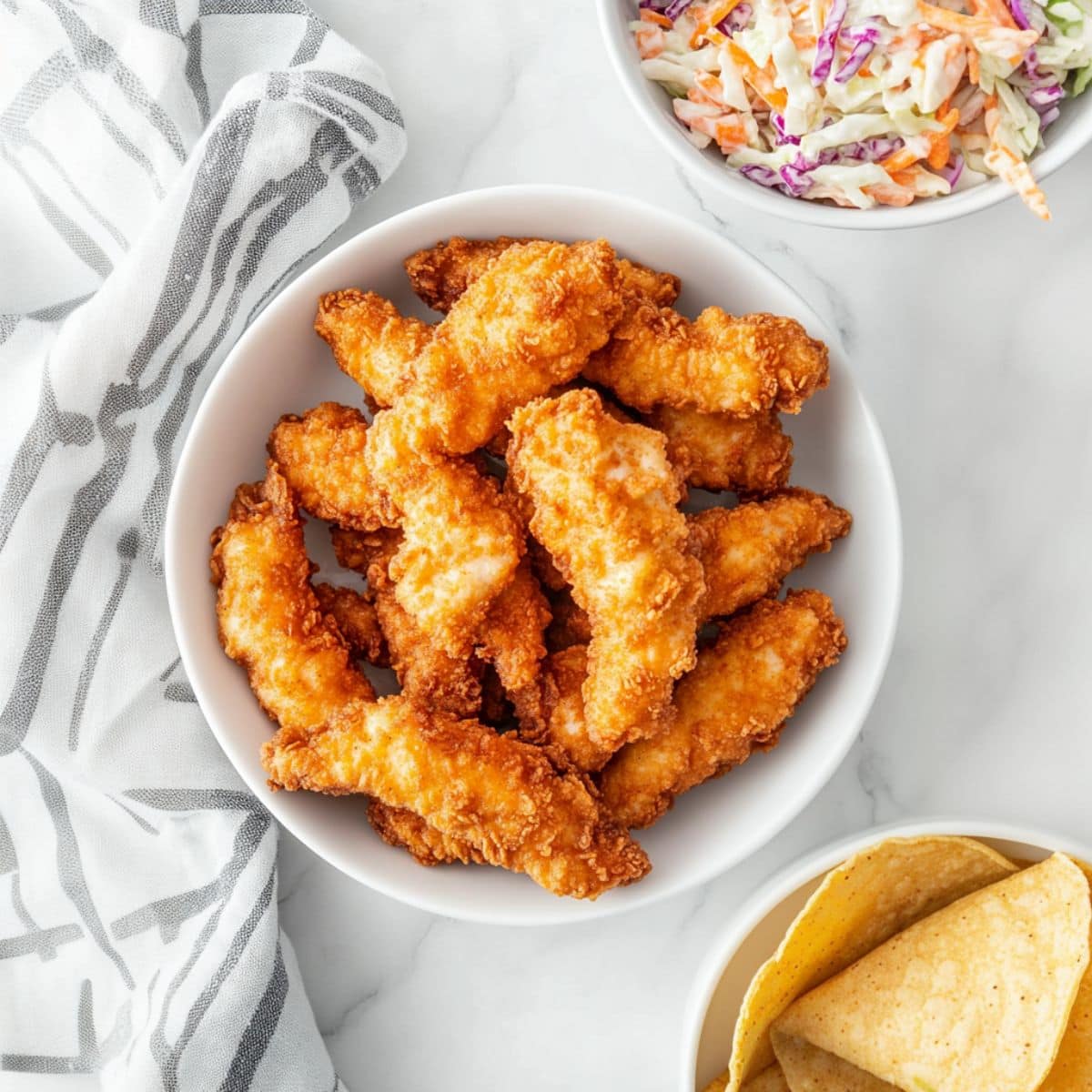 Fried beer battered fish fillets in a white bowl, top view