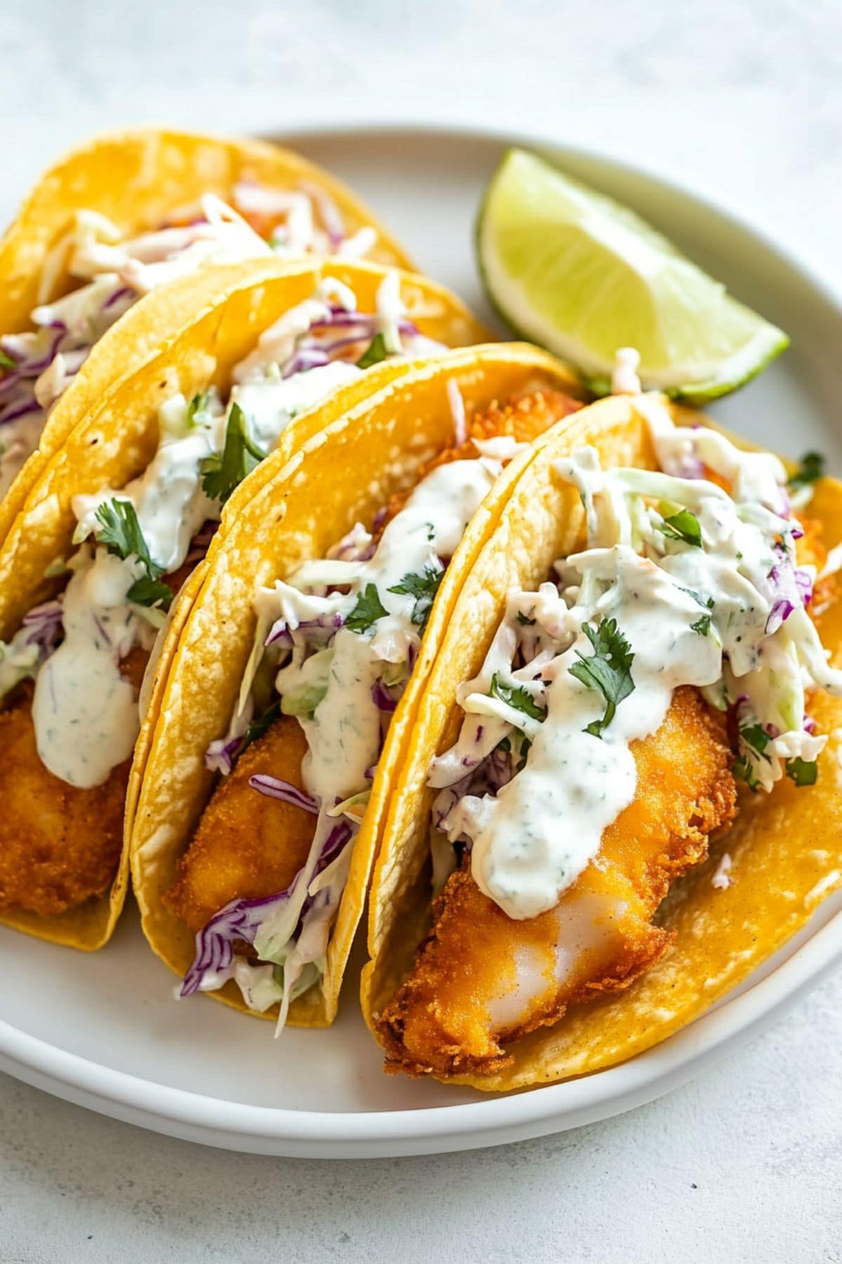 Tacos with beer battered fish and coleslaw drizzled with white Baja-style sauce. 