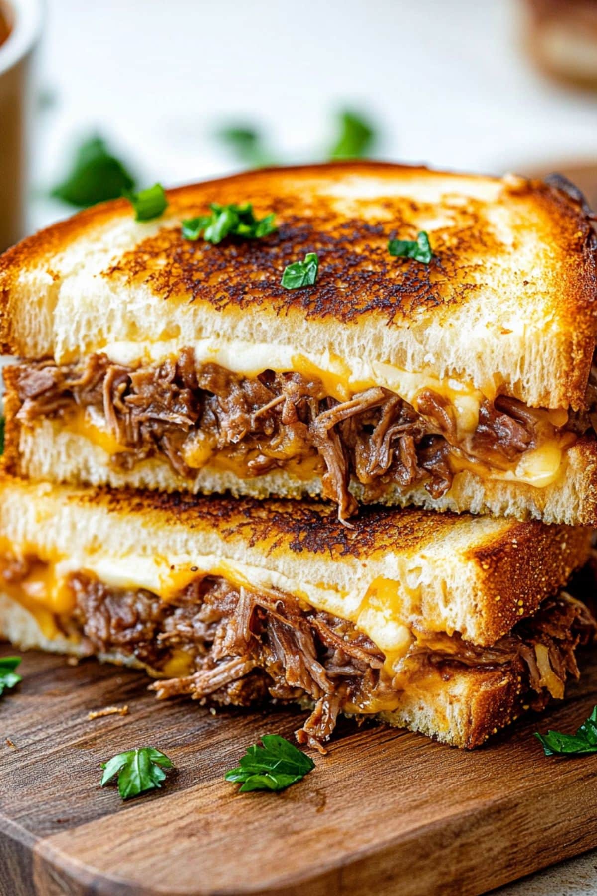 Sliced in half sandwich with cheesy birria filling sitting on a wooden board.