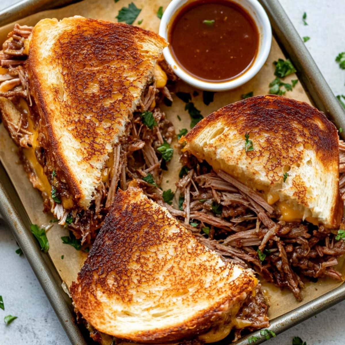 Sliced birria grilled cheese sandwich in a sheet pan. 
