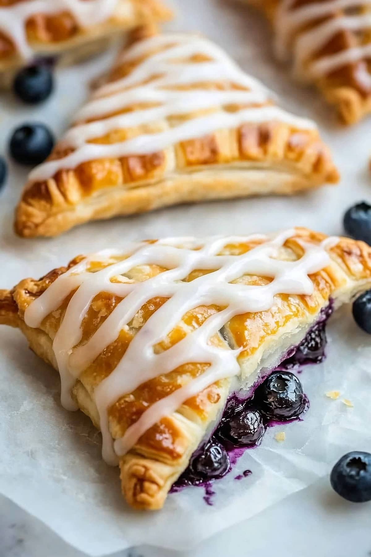 A blueberry turnover with sweet glaze, split open, revealing the juicy, sweet blueberry filling inside, close up