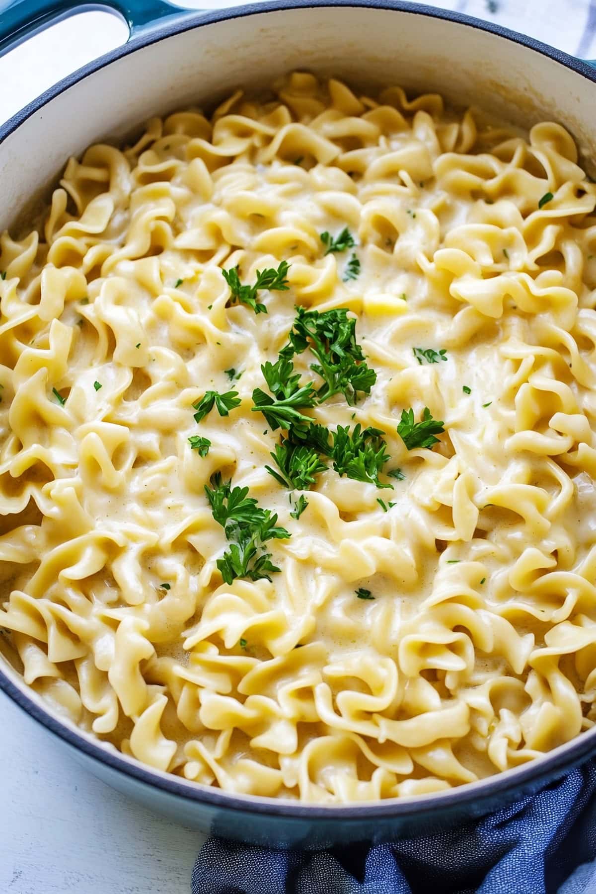 Cafeteria noodles mixed with a bit of butter and herbs in a deep pot.