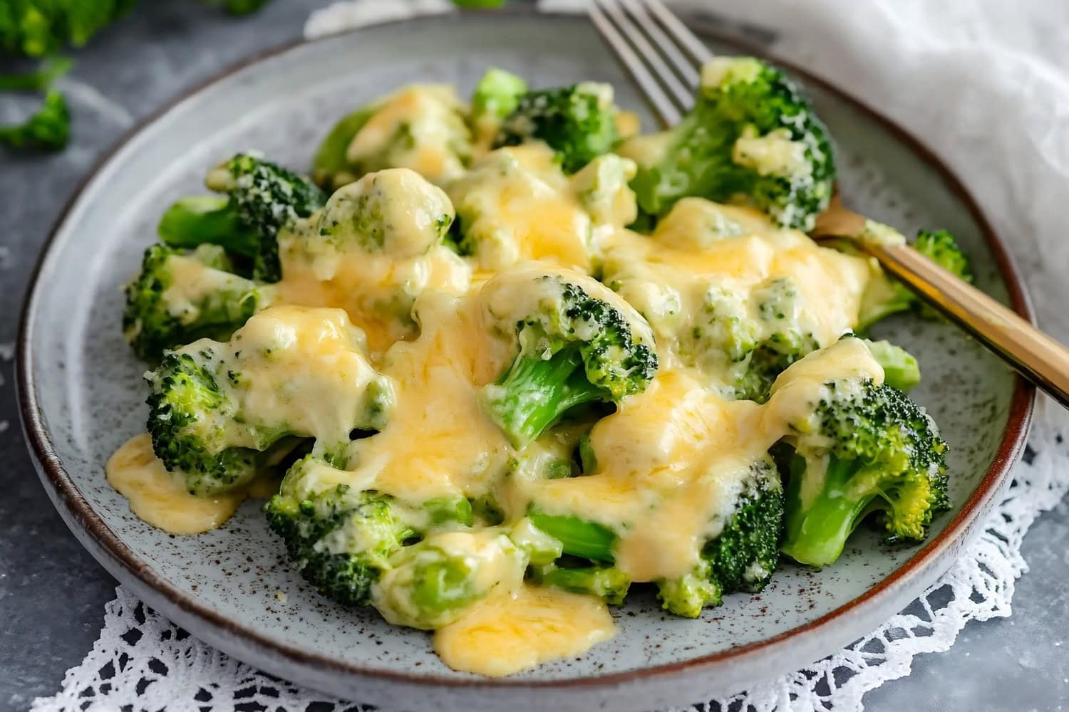 Broccoli florets smothered in cheese sauce, served on a plate.