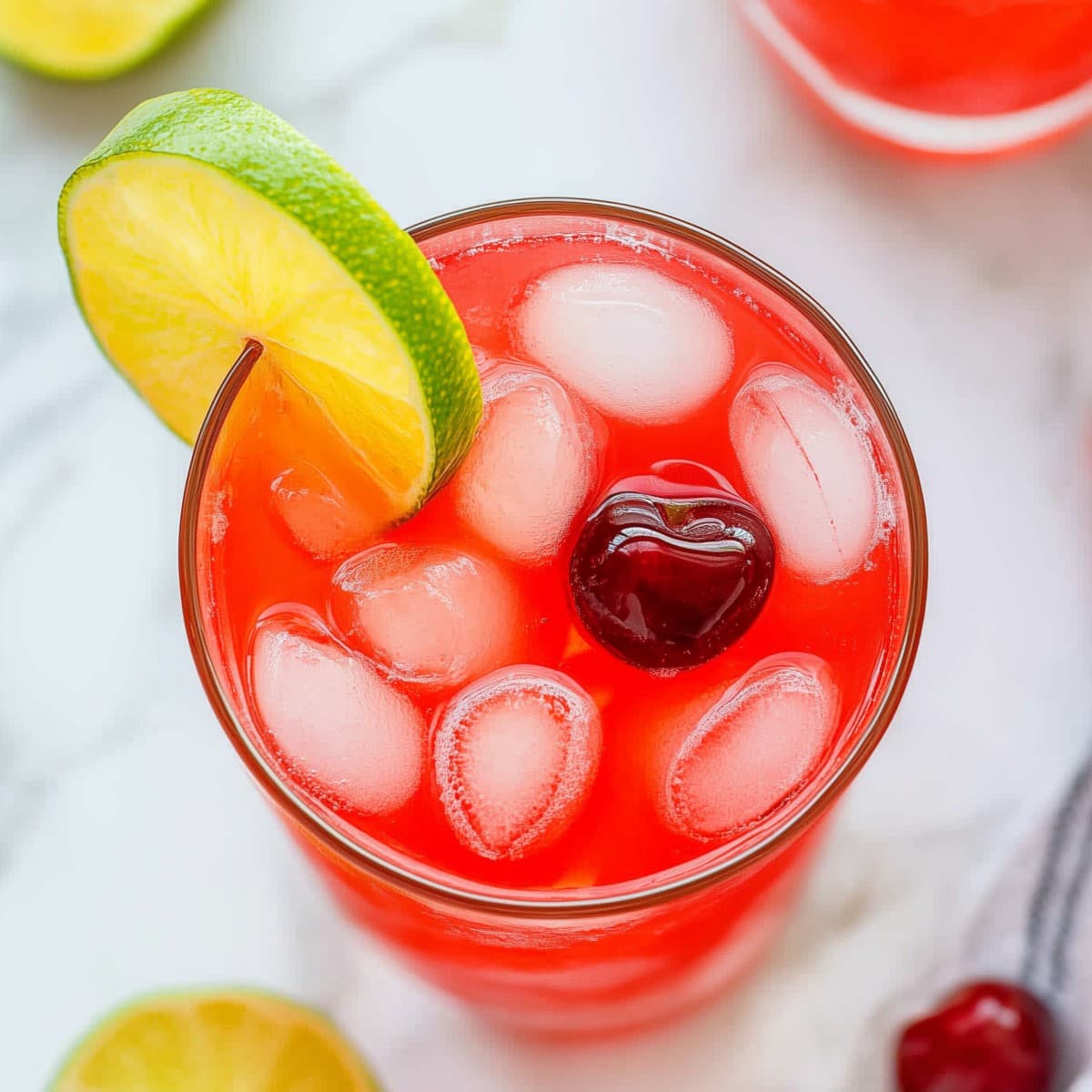 Fizzy cherry limeade with a bright red color and a garnish of cherries, top view.