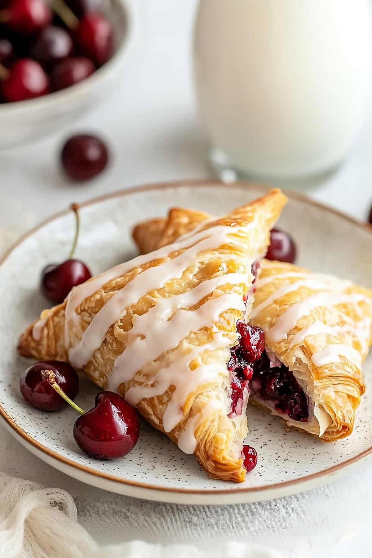 Freshly baked cherry turnovers with glaze on a plate with fresh cherries