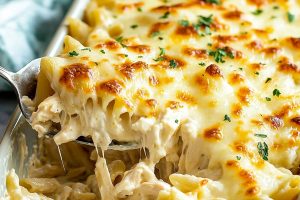 Cheesy homemade chicken alfredo casserole in a spoon, close-up