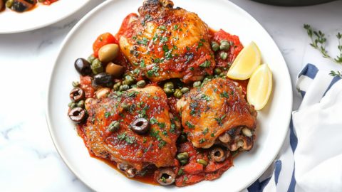 Serving of chicken puttanesca in a white plate.