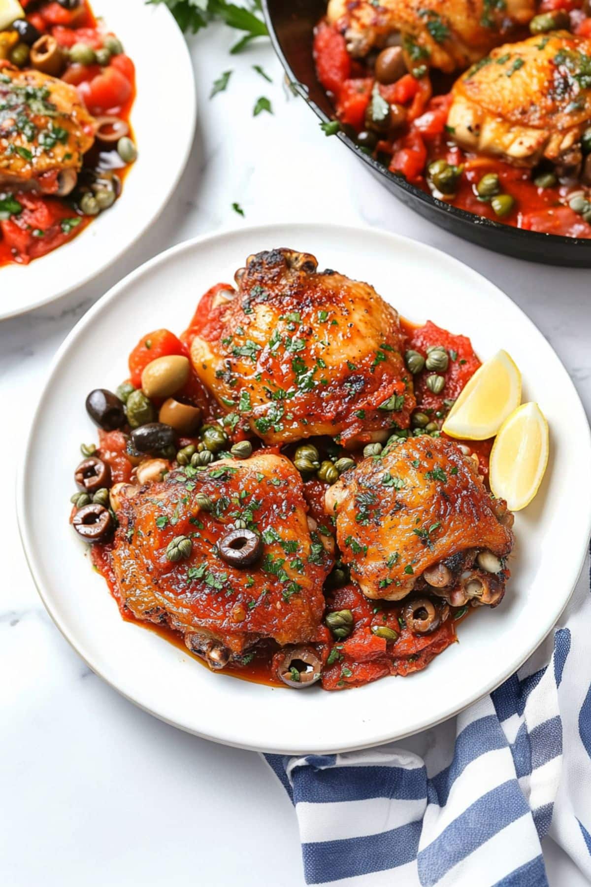 Serving of chicken puttanesca with olives, capers, anchovies, and tomatoes sauce on a plate.