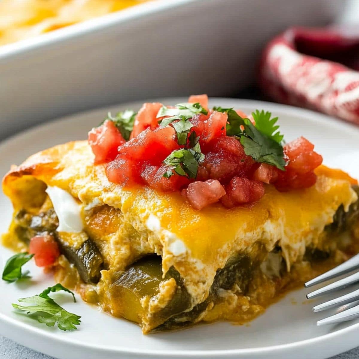 Serving of baked chile relleno casserole on a plate with salsa garnish.