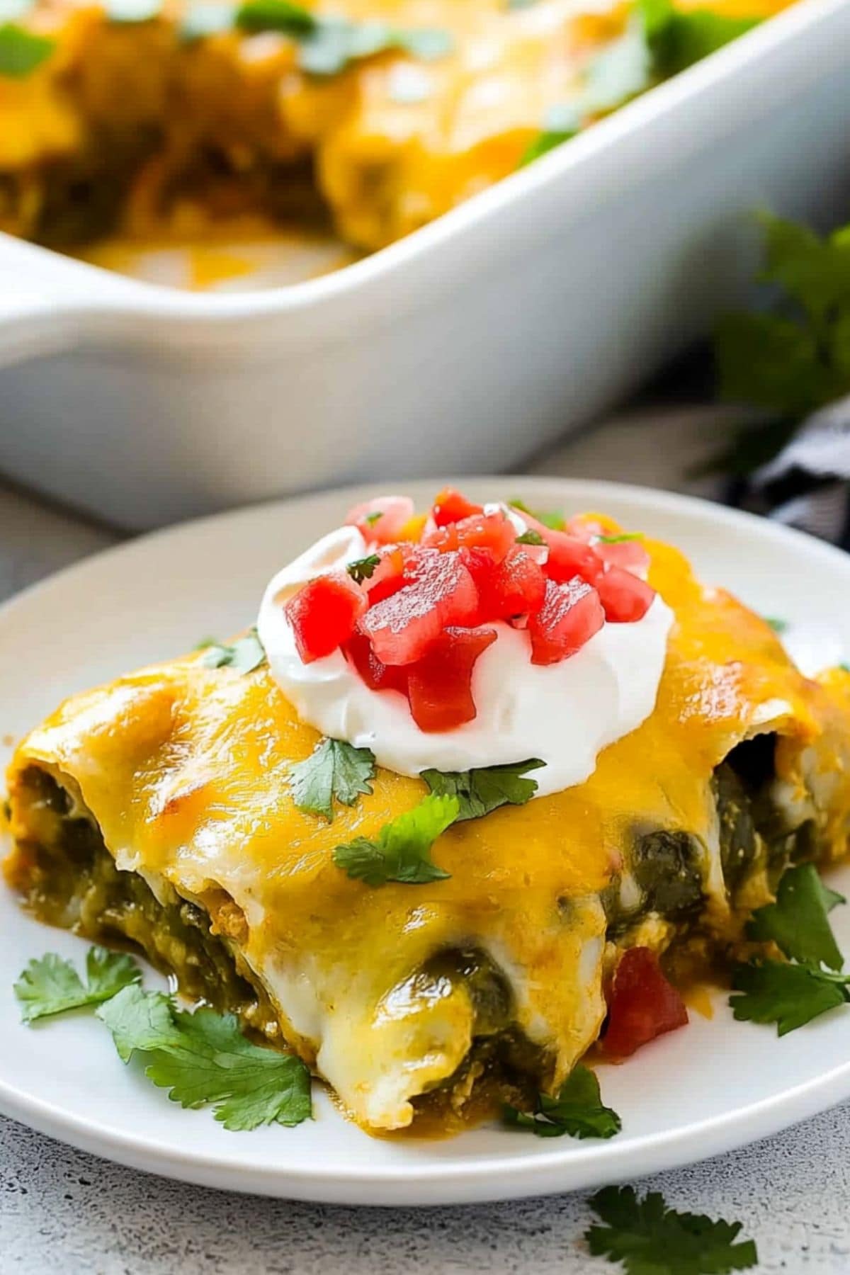 Serving of cheesy relleno casserole on a white plate garnished with salsa and sour cream.