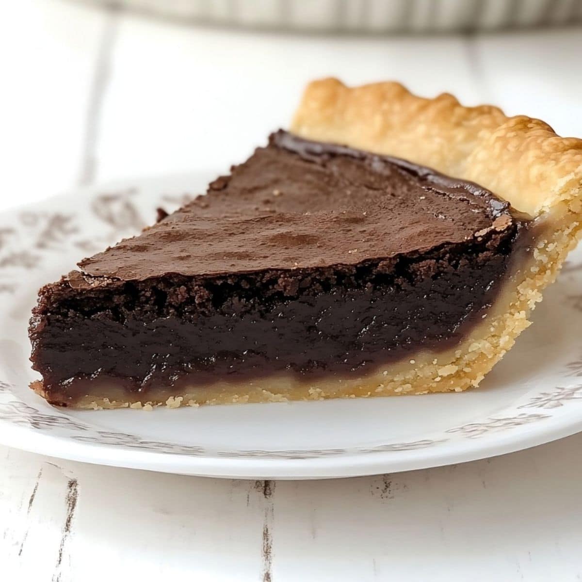 Chocolate fudge pie slice served on a white plate. 