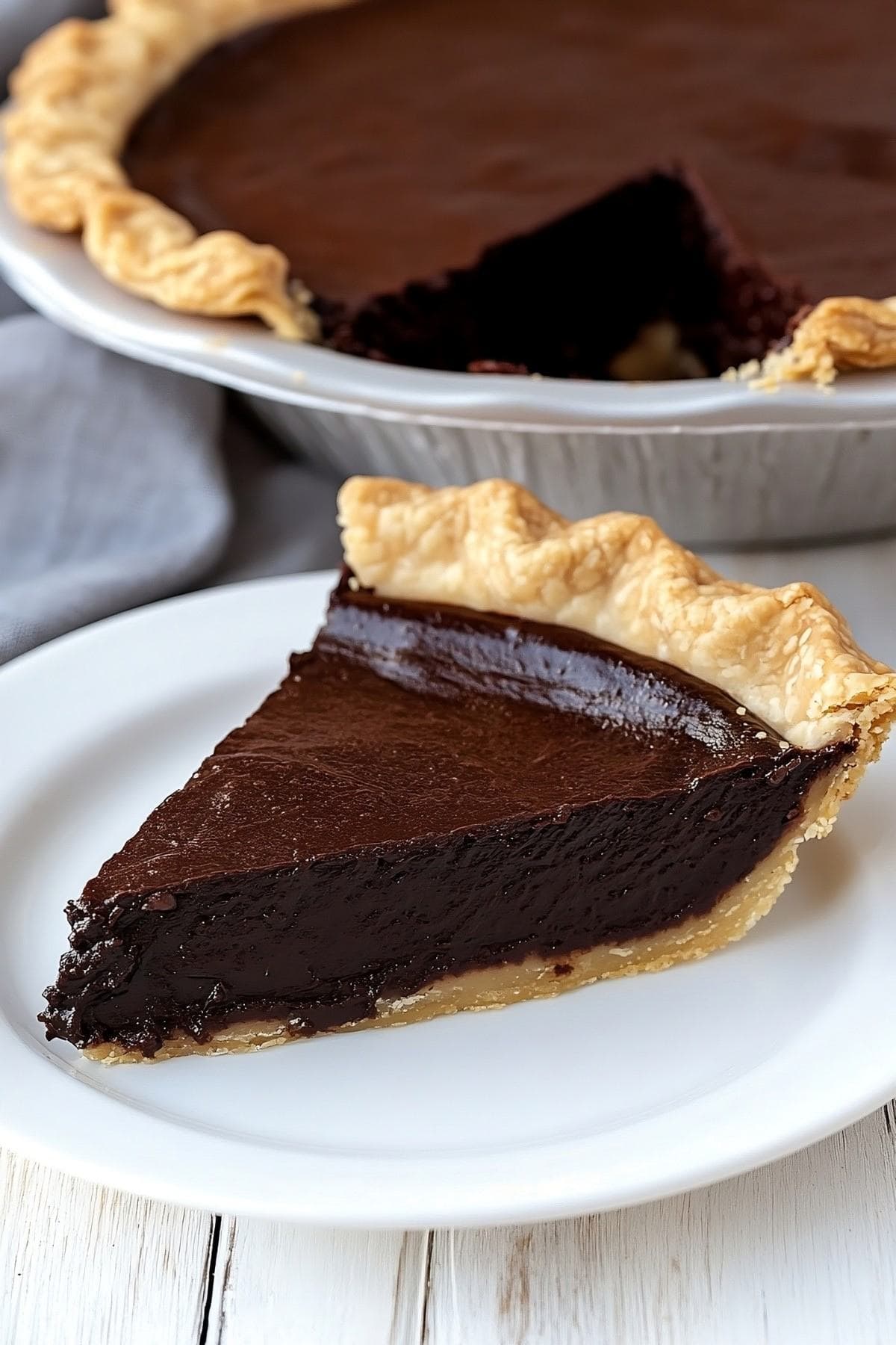 A perfect slice of chocolate fudge pie served in a white plate.