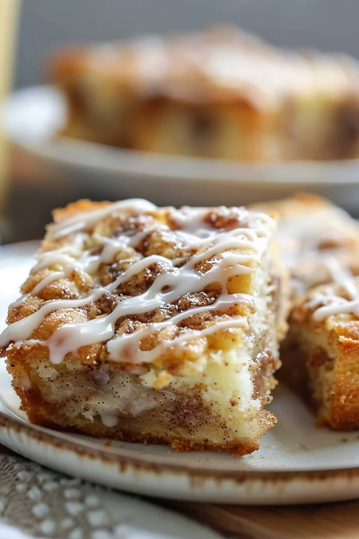 Slice of vanilla sheet cake with cinnamon sugar swirls and vanilla glaze on a plate, close up