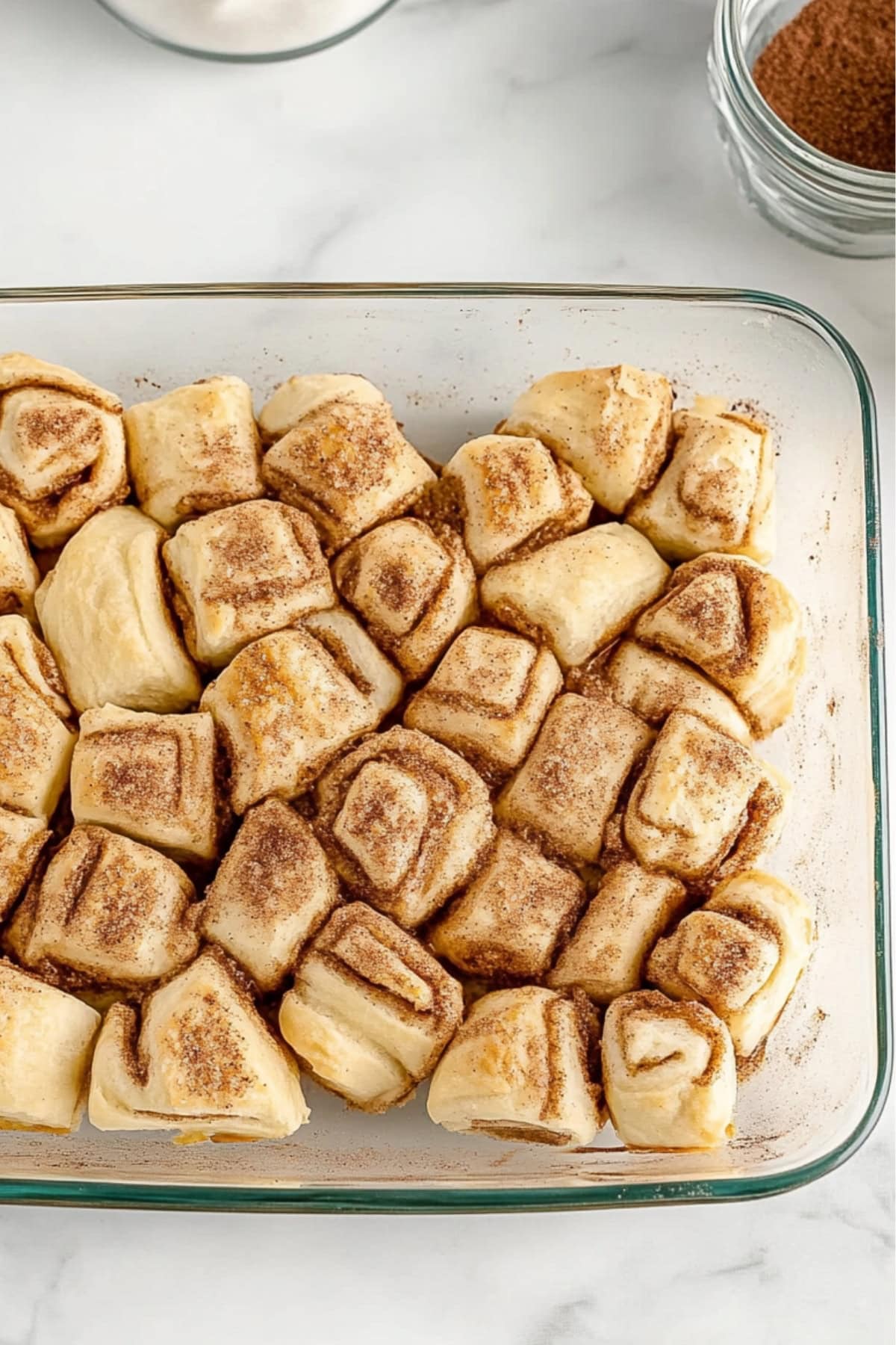 Custardy egg mixture over cinnamon rolls in a baking dish.