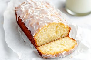 Sliced coconut bread drizzled with a glossy white glaze and topped with shredded coconut.