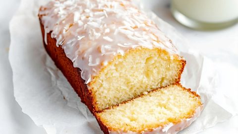 Sliced coconut bread drizzled with a glossy white glaze and topped with shredded coconut.