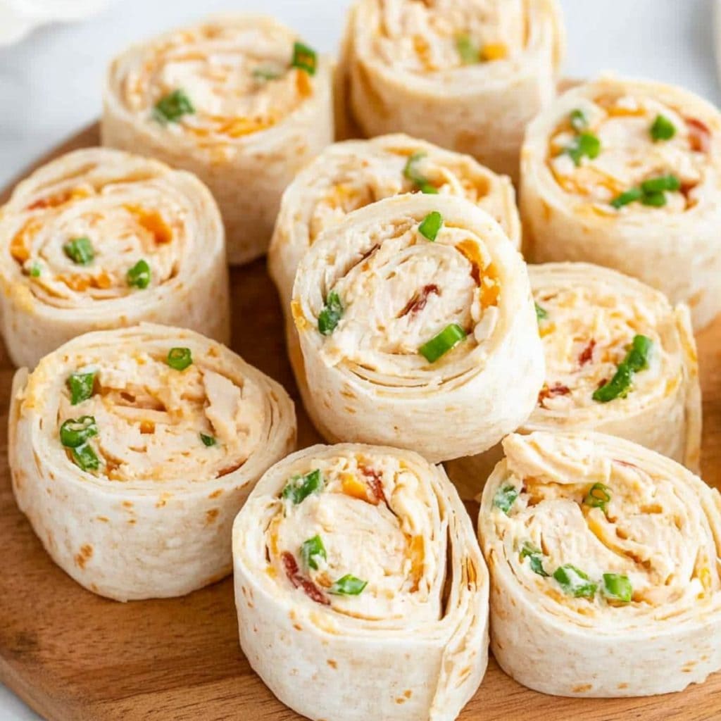 Slices of chicken pinwheels in a round wooden board.