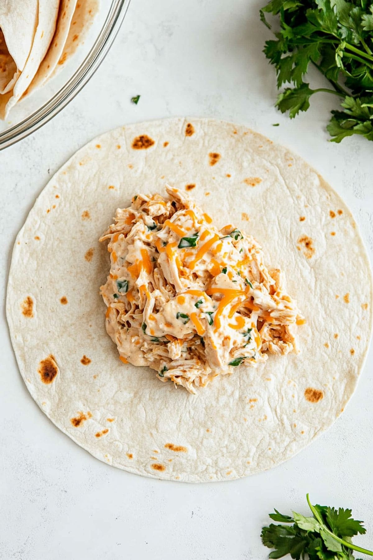 Burrito wrap with chicken mixture on top.