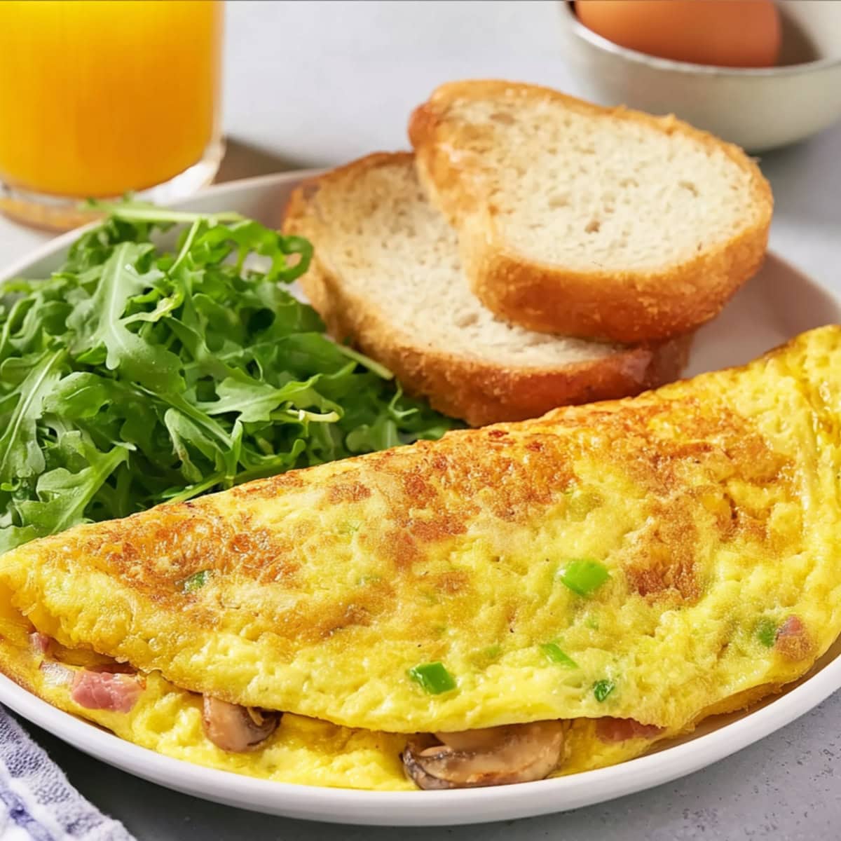 Denver omelette served with aragula  and bread in a white plate.