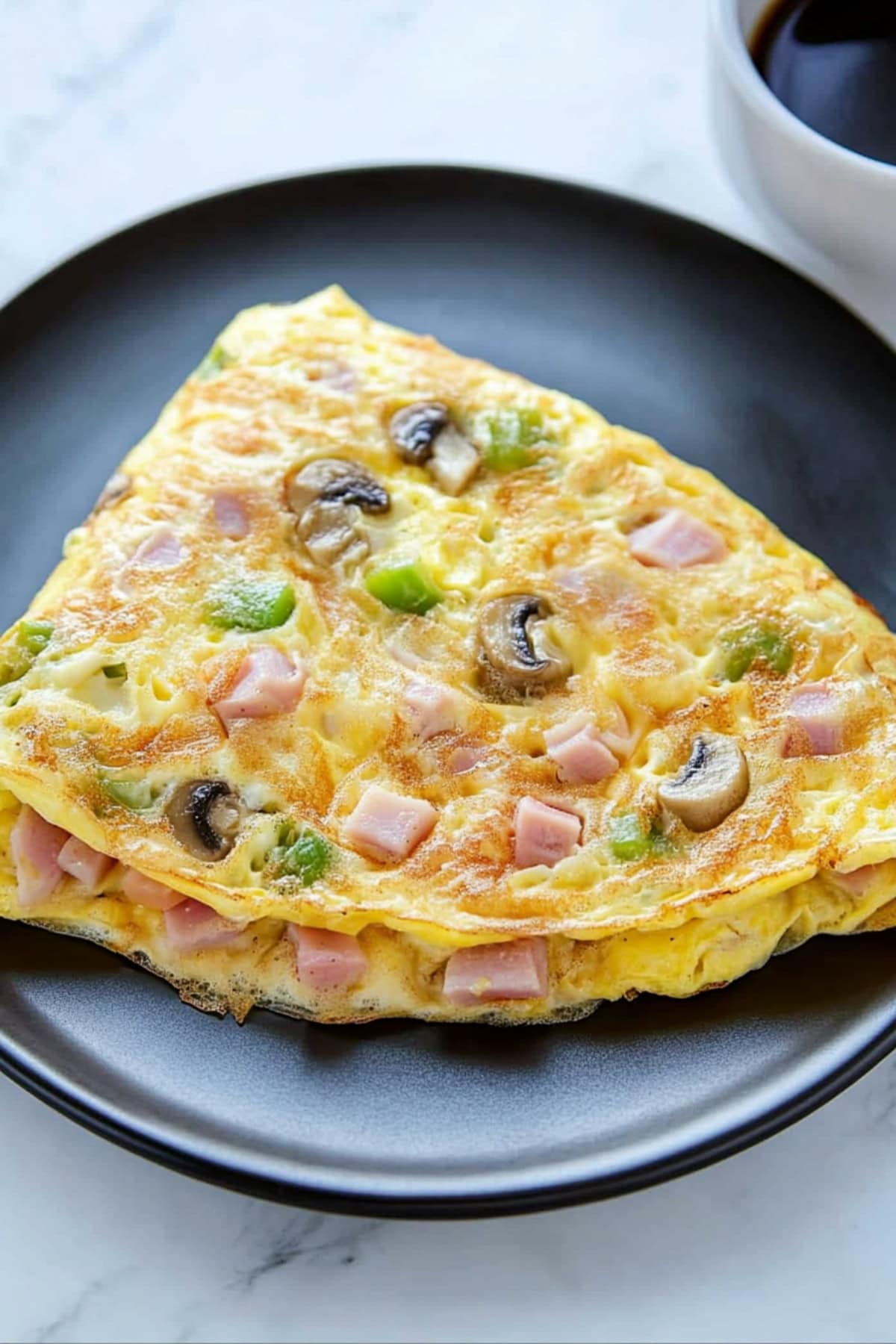 Denver omelette with diced ham, green bell peppers and mushrooms, served with a hot coffee.