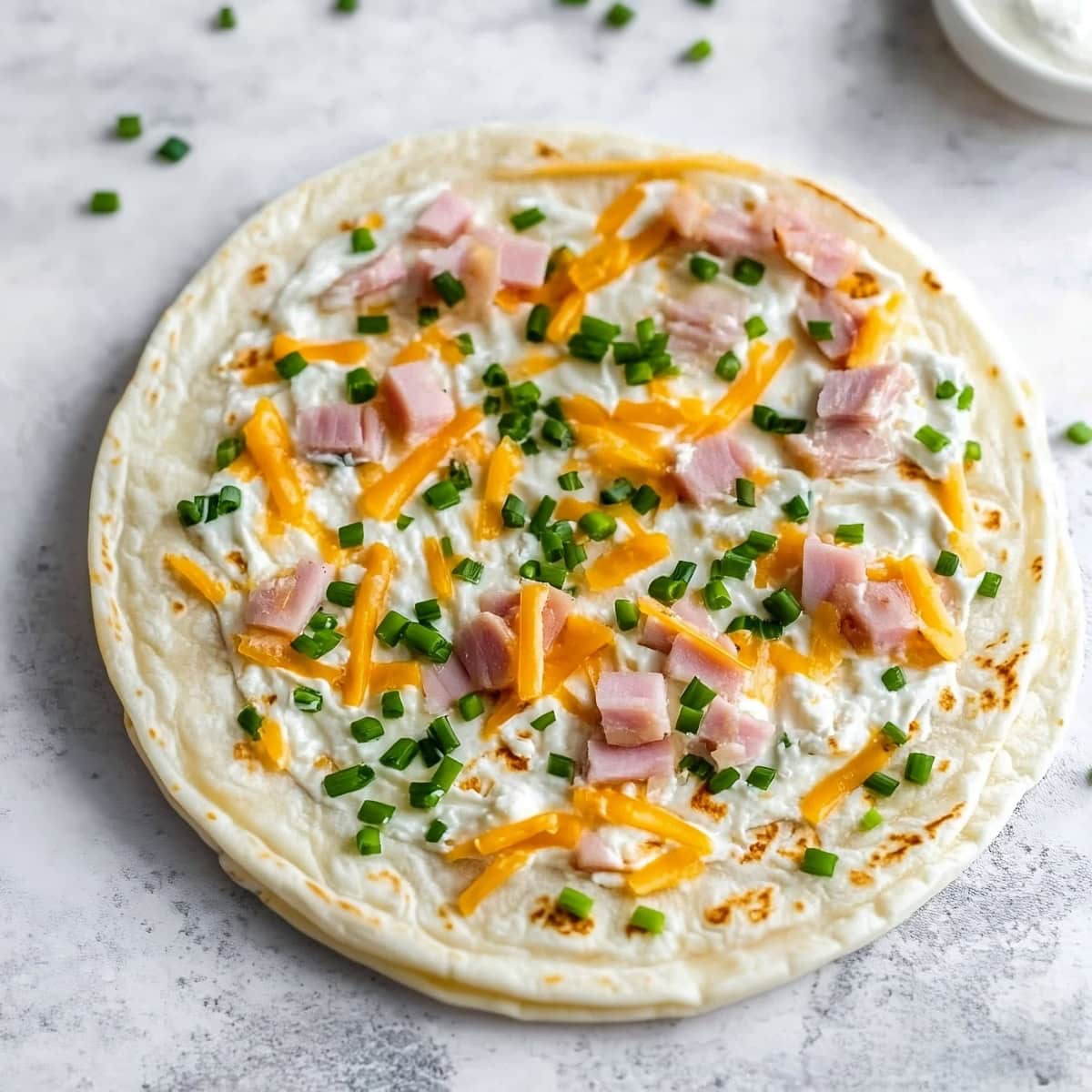 Flour tortillas with cheese, diced ham, chopped chives, and cream cheese.