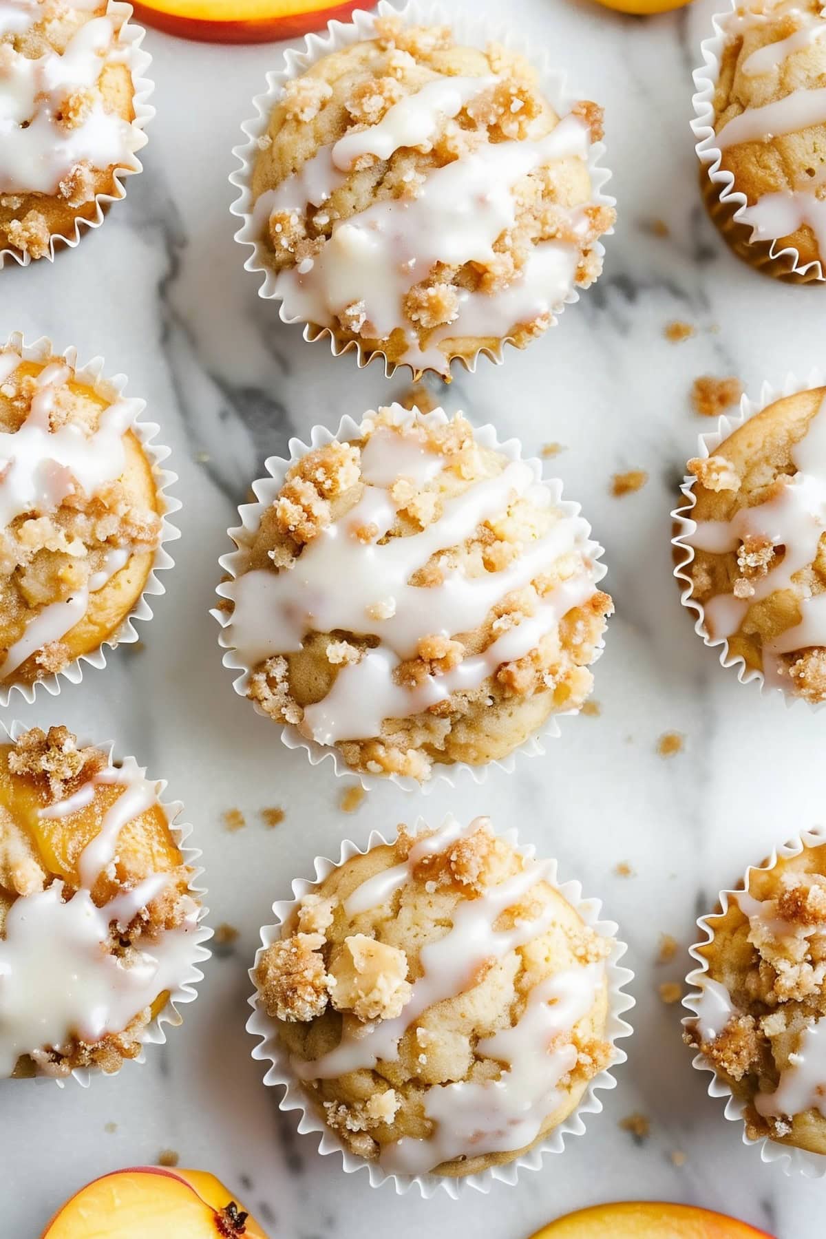 Warm peach streusel muffins with a cinnamon-sugar crumb topping and sweet vanilla glaze.