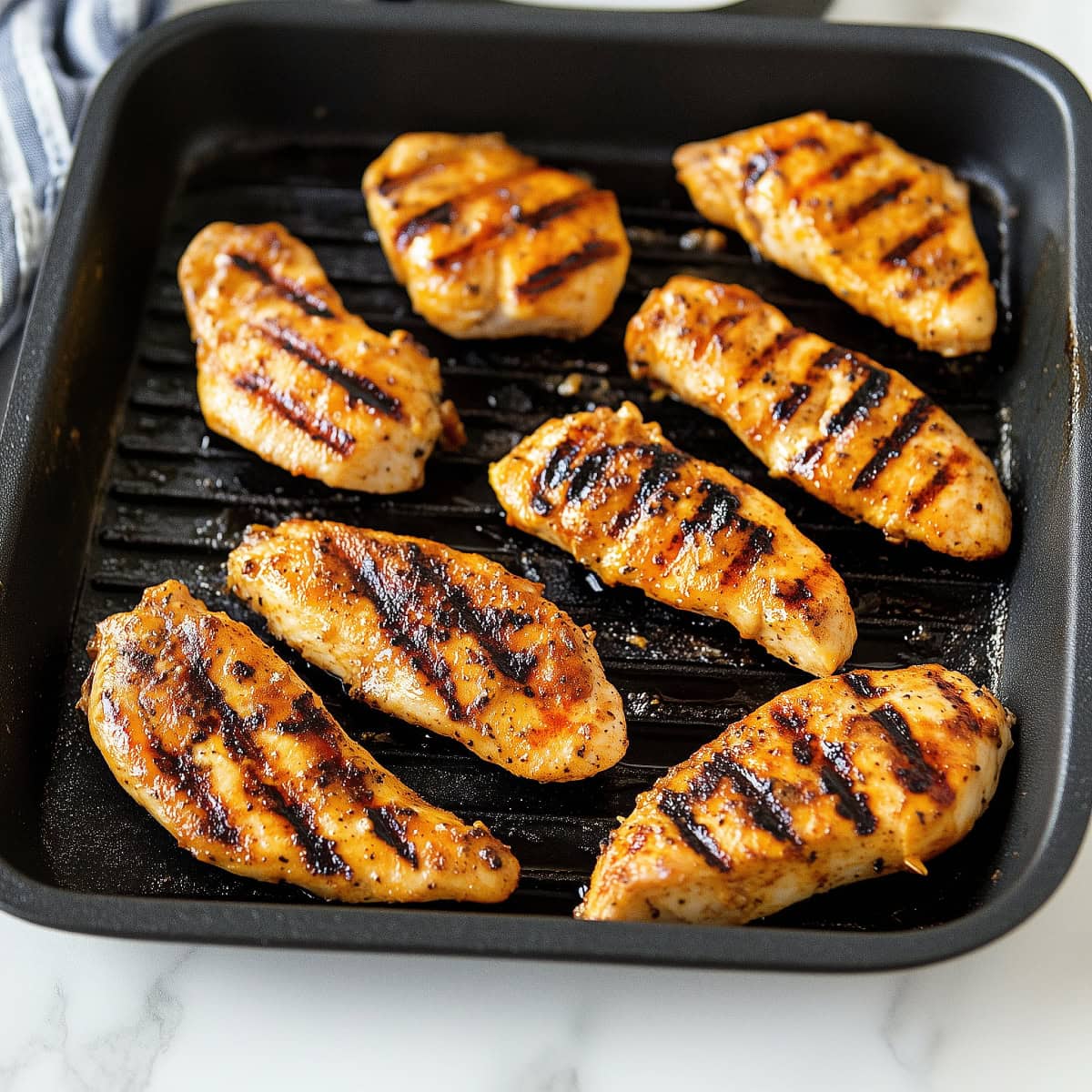 A close-up of perfectly seasoned grilled chicken tenders, served hot.