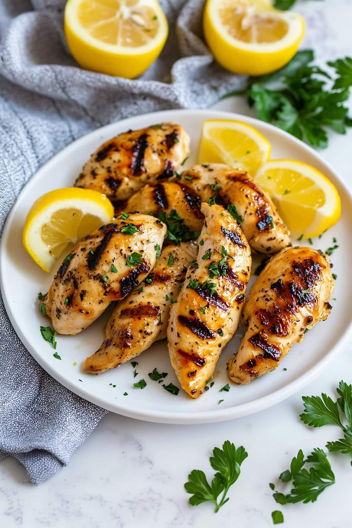 Juicy grilled chicken tenders with charred grill marks on a white plate.