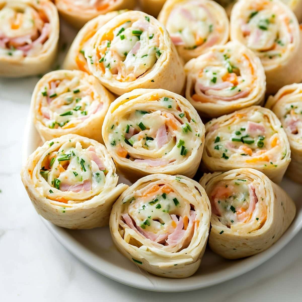 Ham and cheese pinwheels on a platter, perfect for a party appetizer.