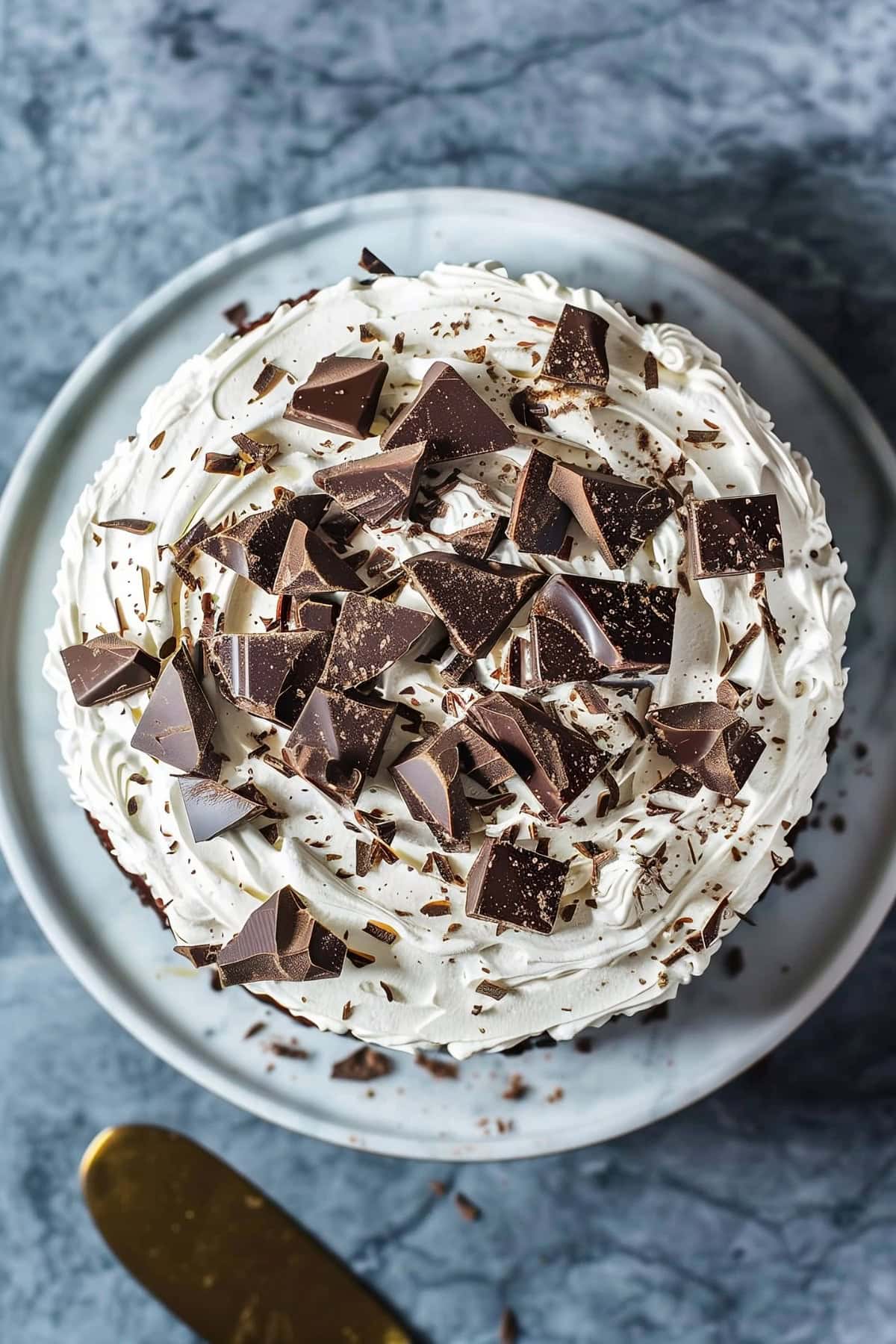 Top down view of chocolate cake with cream cheese frosting and chopped chocolate garnish