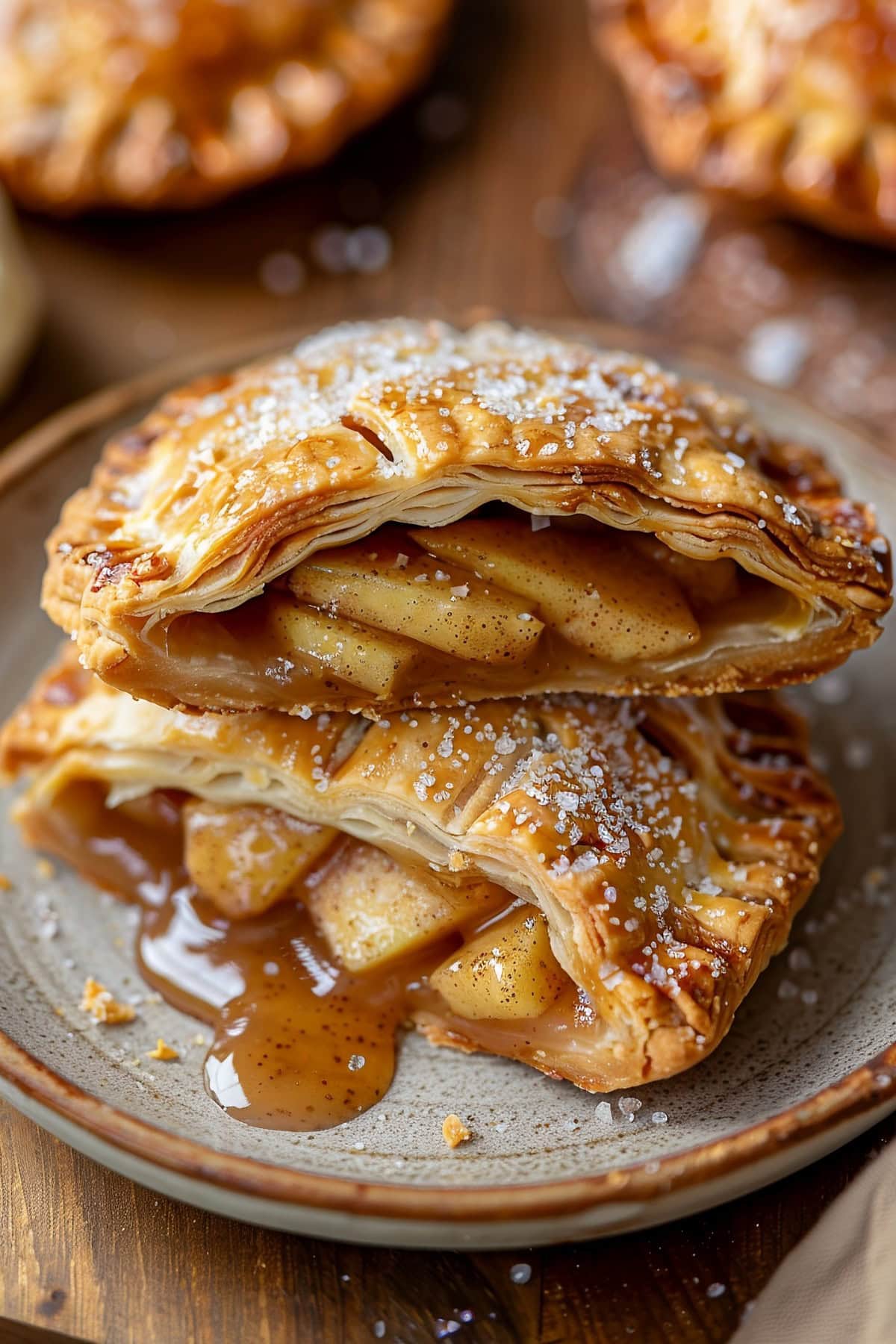 Golden apple hand pies with a flaky, buttery crust, cut in half on a plate.