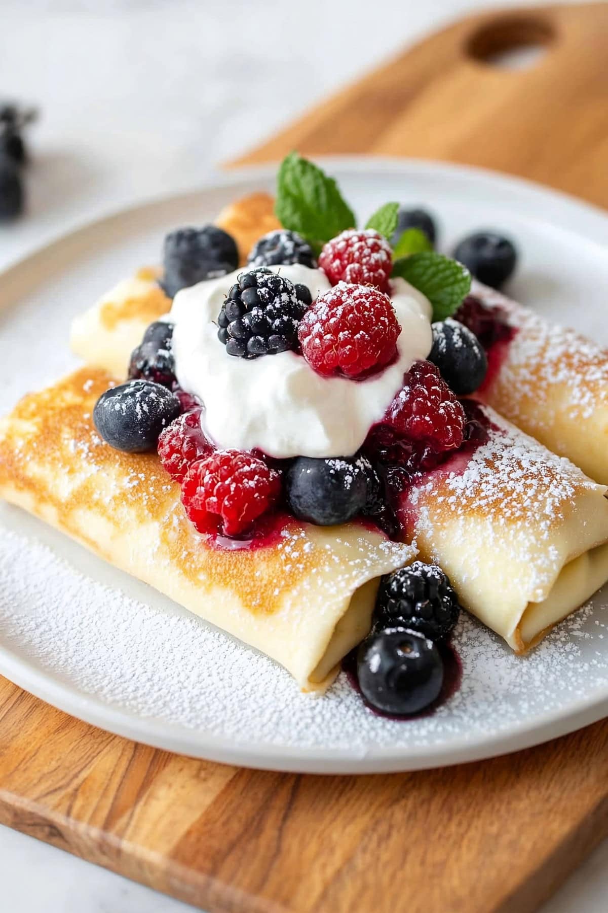 Cheese blintzes topped with berries and whipped cream.