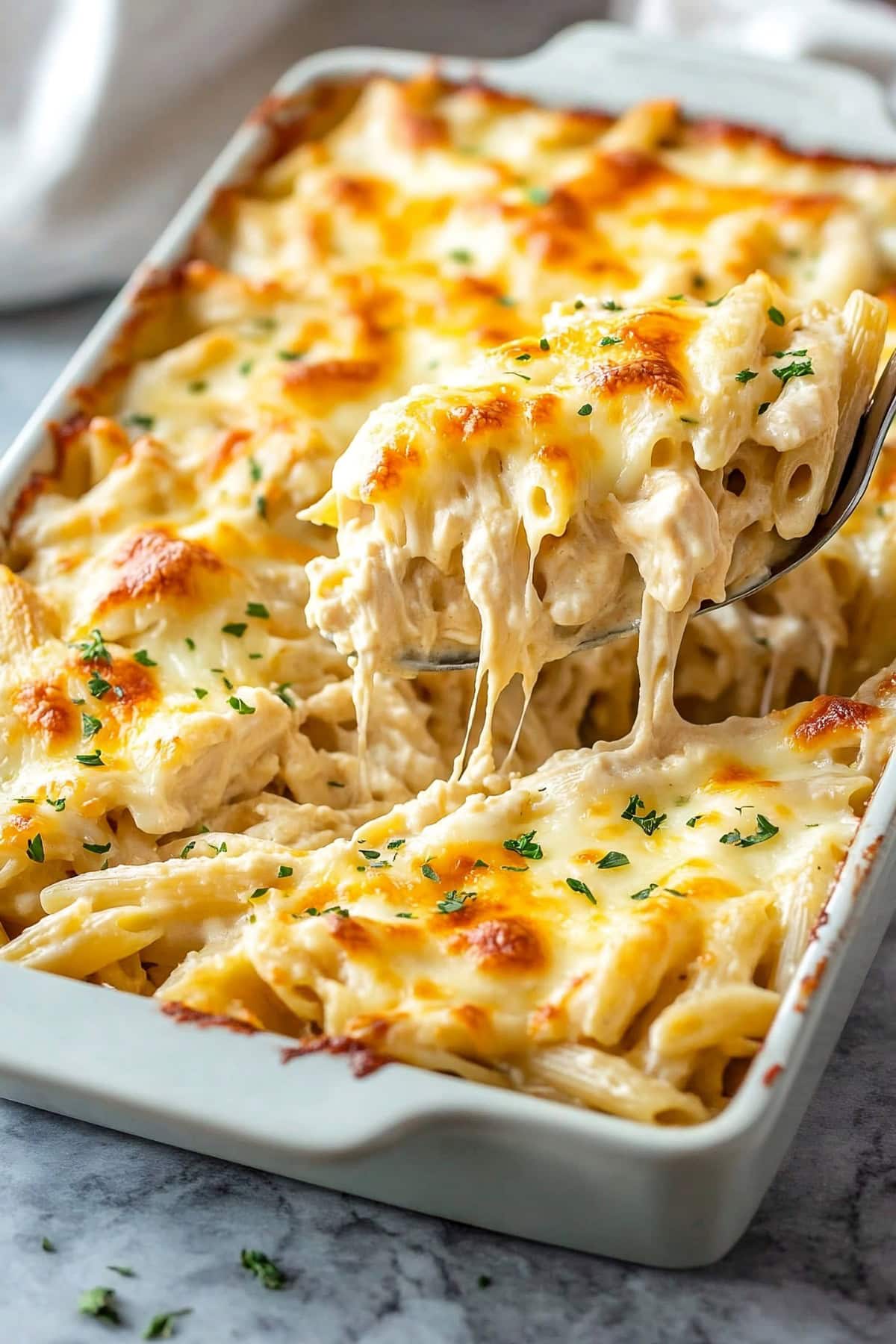 Homemade chicken alfredo casserole, featuring penne pasta sprinkled with herbs.