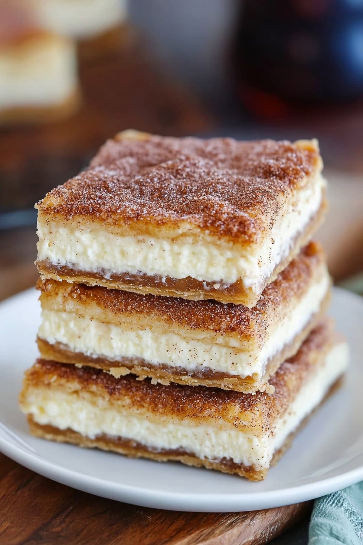 churro cheesecake bars stacked on a white plate, close up